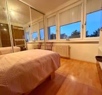 Ložnice v 3-pokojovém bytě s postelí, skříní a podlahou s dřevěným dekorem.