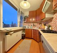 Kuchyně ve 3-pokojovém bytě se světlým nábytkem a podlahou s dřevěným dekorem.