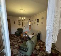 Obývací pokoj v 3-pokojovém bytě se zeleným nábytkem a dekorativním kobercem.