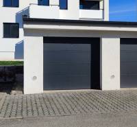 Garáže na ulici Predmerského v Trenčíně s bytovým domem v pozadí.