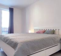 Ložnice v 2-pokojovém bytě se světlým nábytkem a podlahou s dřevěným dekorem.