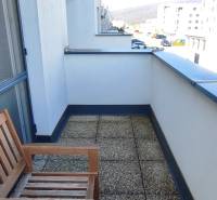 Balkon s lavicí v 2-pokojovém bytě na ulici Predmerského, Trenčín, s výhledem na město.