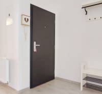 Vstupní chodba se světlými stěnami a podlahou s dřevěným dekorem vede do ložnice.