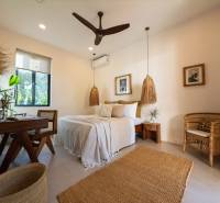 Světlá ložnice se závěsnými lampami a proutěným nábytkem v rodinném domě.