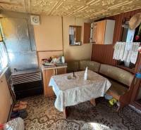 Interiér chaty se starožitným vzorovaným stolem a dřevěnými detaily v Zahradách.