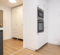 Kuchyně v 1-pokojovém bytě s bílými skříňkami a podlahou s dřevěným dekorem.