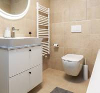 Koupelna v 1-pokojovém bytě s umyvadlovou skříňkou, WC a vanou.