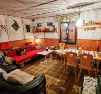 Útulný interiér chaty s dekorovaným stolem, sedačkou a dřevěnými židlemi.