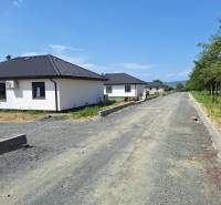 Rodinné domy na ulici Vyšná Šebastová v Prešově obklopené zelení, vedle nedokončené cesty.