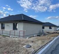 Domy s moderními střechami na ulici Vyšná Šebastová, vedle rodinného domu ve výstavbě.