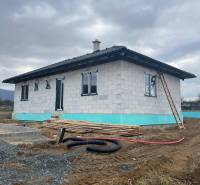 Rodinný dům ve výstavbě, na ulici Vyšná Šebastová, s montážním materiálem a nedokončenou zahradou.