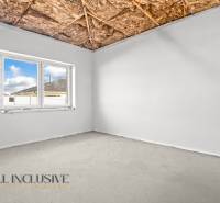 Pokoj s oknem, holým stropem a pohledovým betonem v rodinném domě.