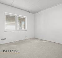 Stavební místnost v rodinném domě s oknem a neupravenou podlahou, připravená k dokončení.