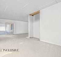 Prostorná místnost v rodinném domě s nedokončenou podlahou a velkým oknem.