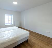 Ložnice s postelí a podlahou s dřevěným dekorem v 2pokojovém bytě.