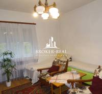 Pohodlný pokoj v rodinném domě s křesly, postelemi a podlahou s dřevěným dekorem.