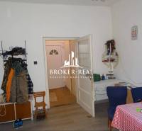 Interiér rodinného domu s podlahou s dřevěným dekorem, jídelním stolem a věšákem na oblečení.