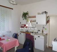 Kuchyně v rodinném domě s klasickým zařízením, záclony, bílý kuchyňský nábytek.