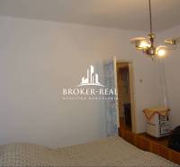 Ložnice v rodinném domě s jednoduchým zařízením a retro vytápěním.