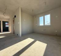 Interiér rodinného domu s nedokončenými stěnami a oknem, podlaha s dřevěným dekorem.