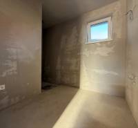 Holé stěny, okno a zásuvka uvnitř rodinného domu; připravené na další úpravy.