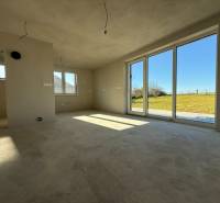 Prostorný interiér rodinného domu s velkými okny a výhledem na zahradu.