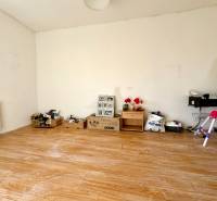 Pokoj v rodinném domě s podlahou s dřevěným dekorem a různými předměty u stěny.