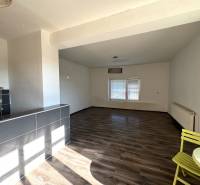 Interiér rodinného domu s prostornou místností, podlaha s dřevěným dekorem a jídelní kout.