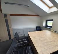 Interiér kanceláře s konferenčním stolem a křesly, podlaha s dřevěným dekorem.