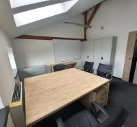 Kancelář s podlahou s dřevěným dekorem, střešním oknem a černými židlemi.