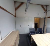 Kanceláře se stolem, černými židlemi, skříňkami a bílou tabulí.