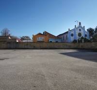 Prázdný pozemek na bydlení v Nových Zámcích, obklopený historickými budovami a lékárnou.