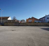 Městský prostor v Nových Zámcích vhodný na pozemky - bydlení, obklopený budovami a dřevěnými domy.