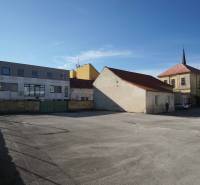 Parkoviště obklopené budovami v Nových Zámcích, ideální pro pozemky - bydlení.