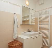 Koupelna v 2-pokojovém bytě s bílým nábytkem, zrcadlem a ručníkem.