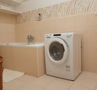 Koupelna s vanou, pračkou a policí v 2-pokojovém bytě.
