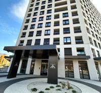 Výšková budova na Karpatské ulici v Popradu s moderním vstupem a oblými chodníky.