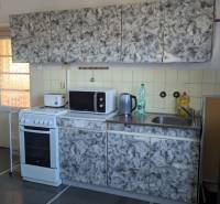 Kuchyně s obkladem, sporákem a krbem v rodinném domě, podlaha s dřevěným dekorem.