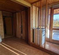 Interiér rodinného domu s dveřmi na terasu a stěnami s dřevěným dekorem.