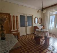 Interiér rodinného domu s barevnou dlažbou, květinovou vázou a záclonami.