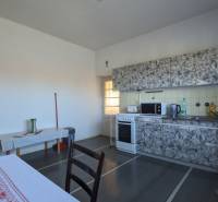 Kuchyně v rodinném domě s kamny a kuchyňskou linkou, podlaha s dřevěným dekorem.