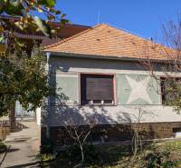 Rodinný dům ve Vráblech obklopený stromy a zahradou se zeleným listím.