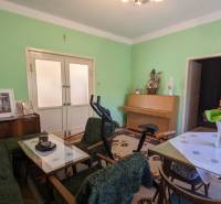 Obývací pokoj v rodinném domě s nábytkem, cvičebním zařízením a zelenými stěnami.