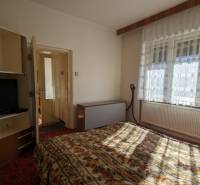 Ložnice v rodinném domě s televizorem a květinovým vzorem ložního prádla.