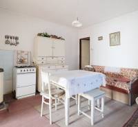 Jídelna s plynovým sporákem, stolem a pohovkou v rodinném domě, podlaha s dřevěným dekorem.