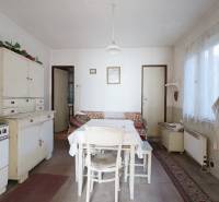 Kuchyně v rodinném domě s retro nábytkem, stolem a umyvadlem, podlaha s dřevěným dekorem.