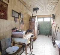 Interiér rodinného domu s žebříkem vedle vyšívané tapisérie. Podlaha s dřevěným dekorem.