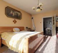 Ložnice v rodinném domě s dřevěným nábytkem, obrazem a lustrem.