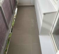 Úzký balkon s keramickou dlažbou v 1-pokojovém bytě.