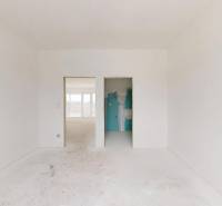 Interiér rodinného domu se světlými stěnami a otevřenými dveřmi do další místnosti.